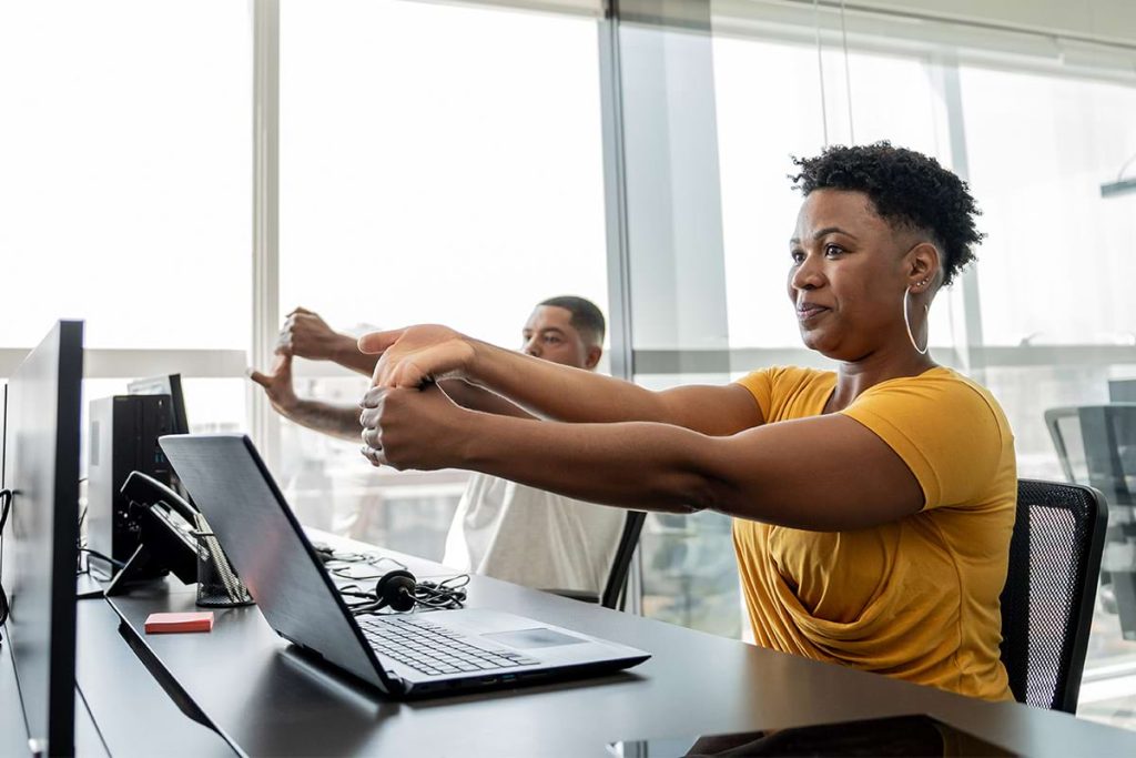 Office workers doing stretching exercises at their desks